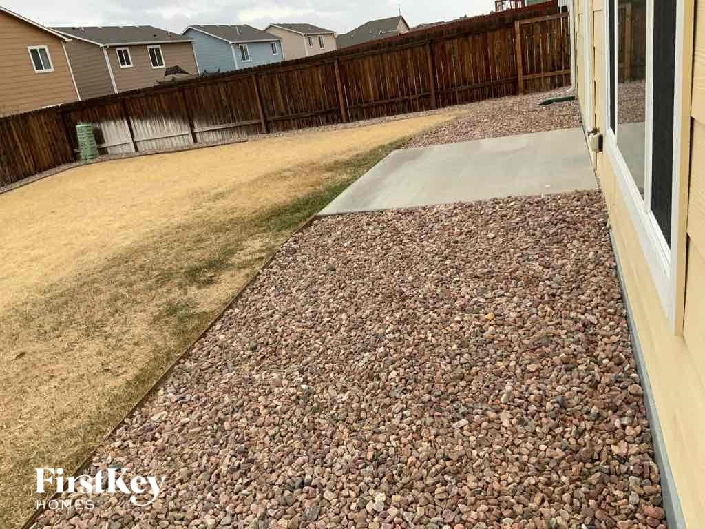 a backyard with a gravel driveway and a house