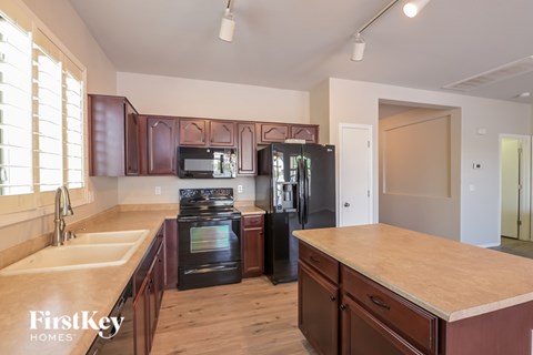 A kitchen with wooden cabinets and a black refrigerator.