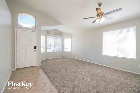 an empty living room with a ceiling fan and a white door