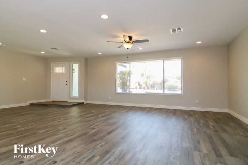 an empty living room with wood floors and a ceiling fan
