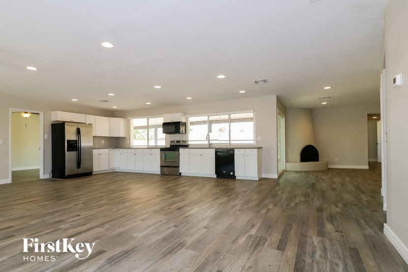 an open kitchen and living room with hardwood flooring and white cabinets