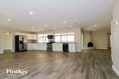 an open kitchen and living room with hardwood flooring and white cabinets