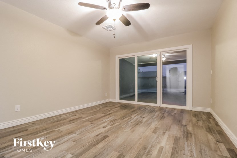 an empty living room with a ceiling fan and sliding glass doors