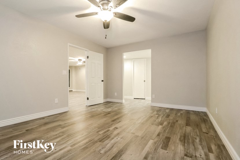 an empty living room with wood flooring and a ceiling fan