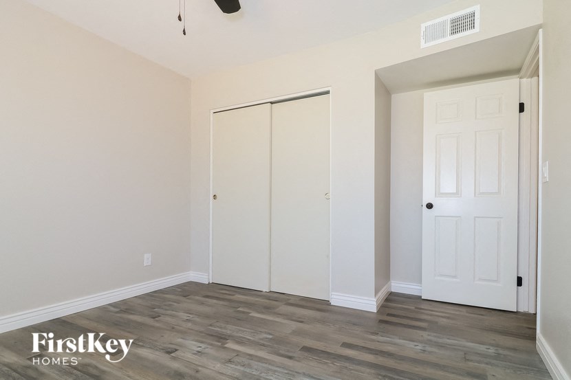 a bedroom with white walls and wood flooring and a closet