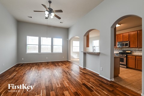 A spacious room with wooden floors and a ceiling fan.