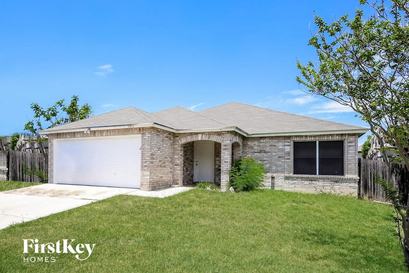 A house with a garage and a tree in front of it.