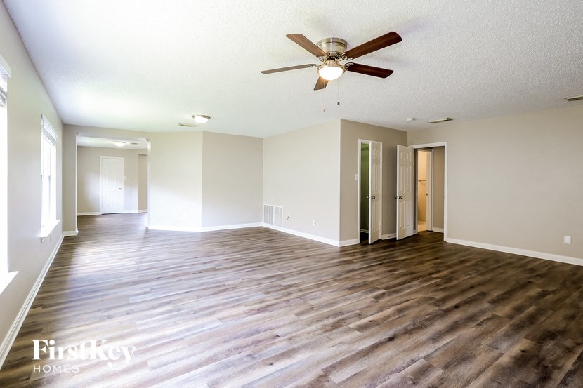 A spacious room with wooden floors and a ceiling fan.