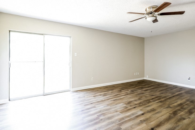 A room with a ceiling fan and sliding glass doors.