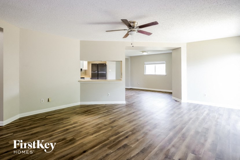 A spacious room with wooden floors and a ceiling fan.