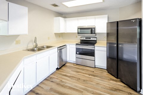 A kitchen with white cabinets and a black refrigerator.