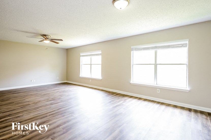A room with a ceiling fan and two windows.
