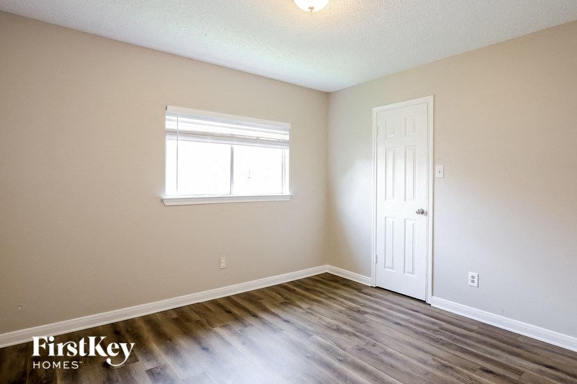 A room with a white door and a window with white blinds.