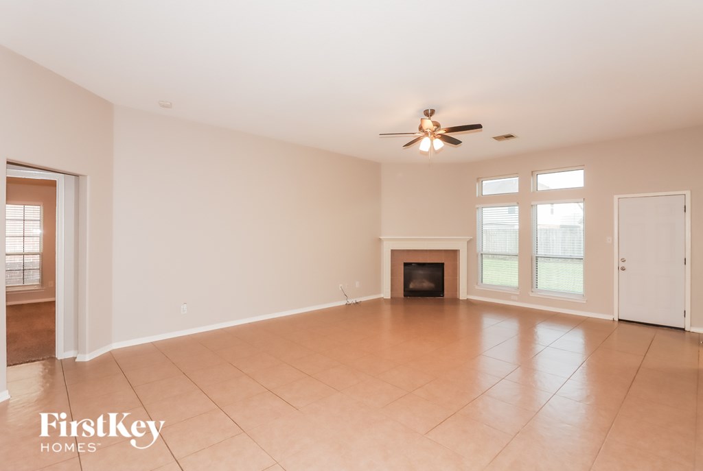 A spacious room with a fireplace and a ceiling fan.