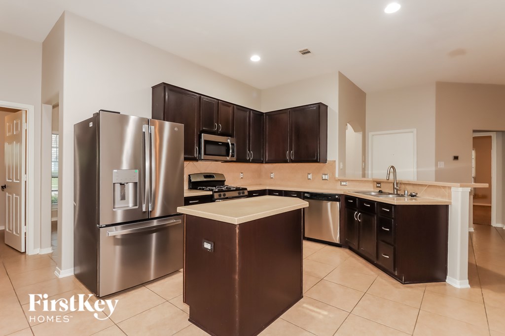 A kitchen with a refrigerator, microwave, and oven.