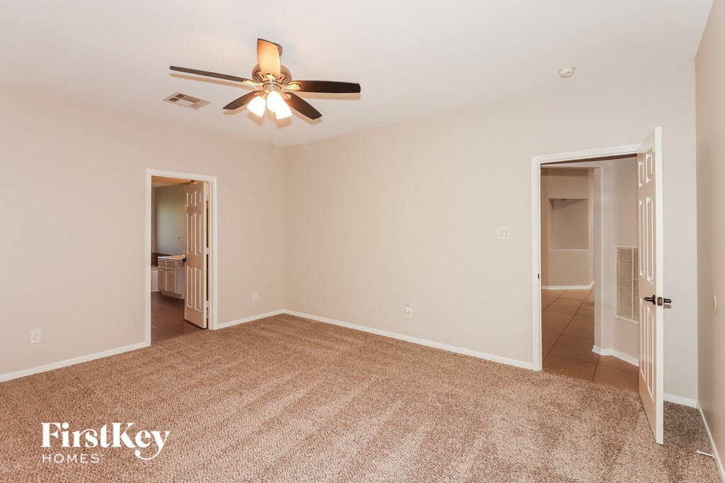 A spacious room with a ceiling fan and two doors.