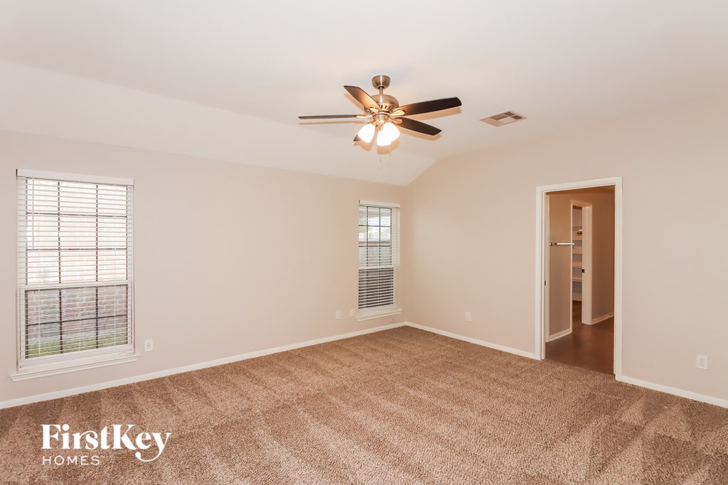 A room with a ceiling fan and a window with blinds.