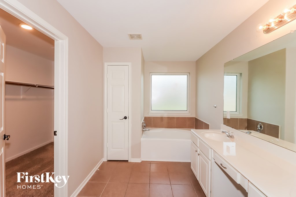 A bathroom with a tub, sink, and mirror.