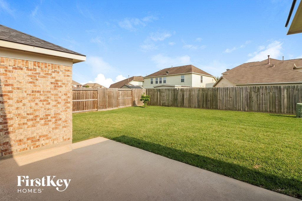 A backyard with a wooden fence and a green lawn.