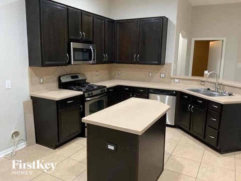A kitchen with black cabinets and a white island.