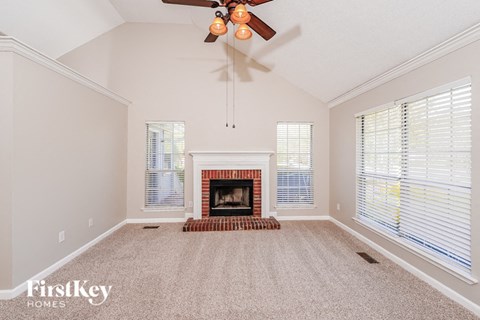 A spacious living room with a fireplace and a ceiling fan.