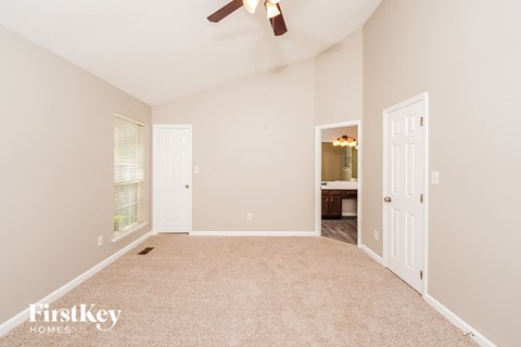 A spacious room with a carpeted floor and a ceiling fan.