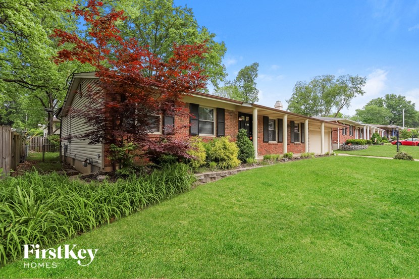 a brick house with a green lawn and trees