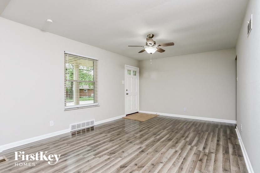 an empty living room with wood floors and a ceiling fan