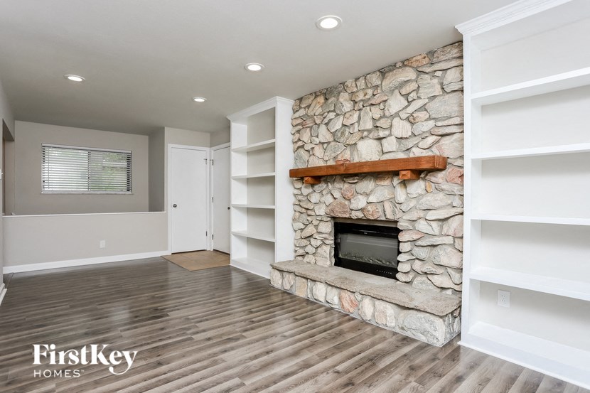 a living room with a stone fireplace and white shelves