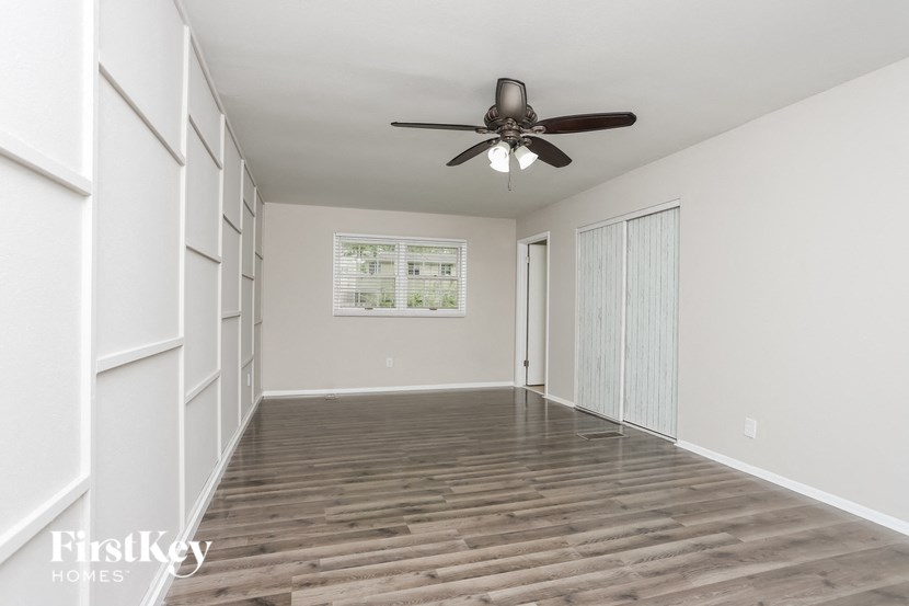 a empty living room with a ceiling fan and a closet