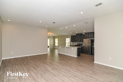 A spacious kitchen and living room with wooden flooring and a kitchen island.