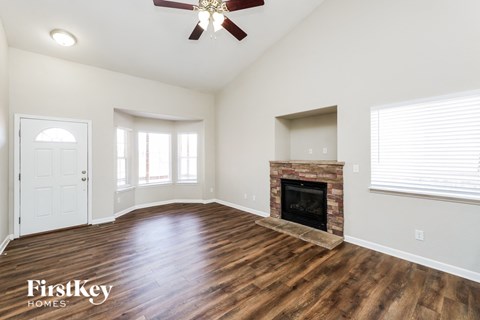 A spacious living room with a fireplace and a ceiling fan.