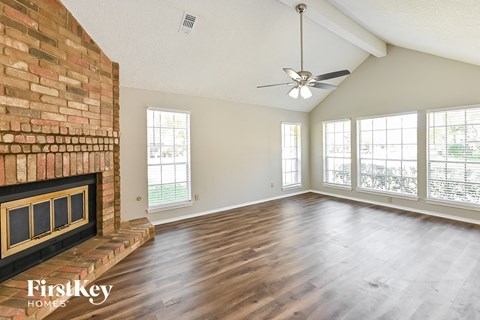 the living room has a brick fireplace and hardwood floors