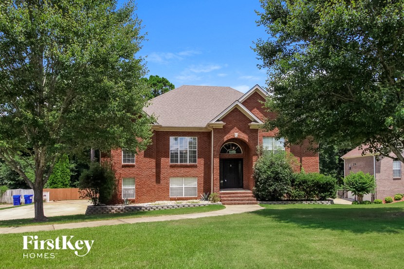 a brick house with a lawn and trees