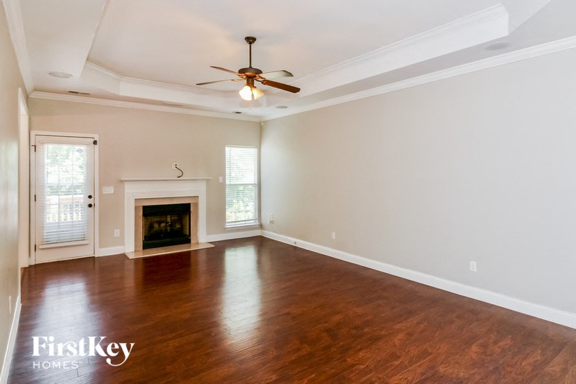 an empty living room with a ceiling fan and a fireplace