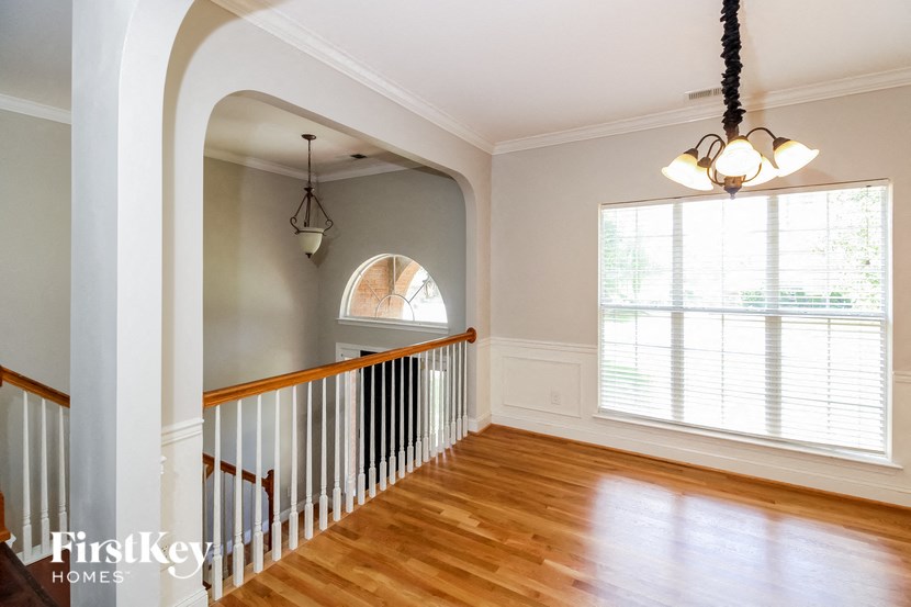 a living room with a staircase and a large window and wood floors
