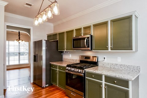 a kitchen with green cabinets and stainless steel appliances