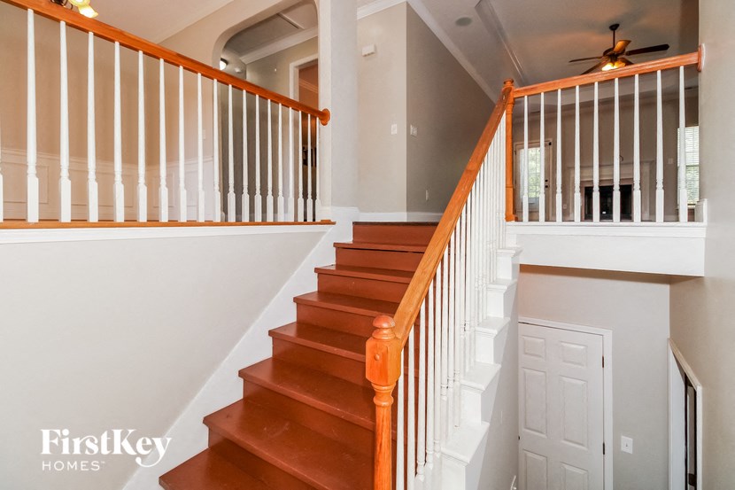 a stairway in a home with a white door and a wooden railing