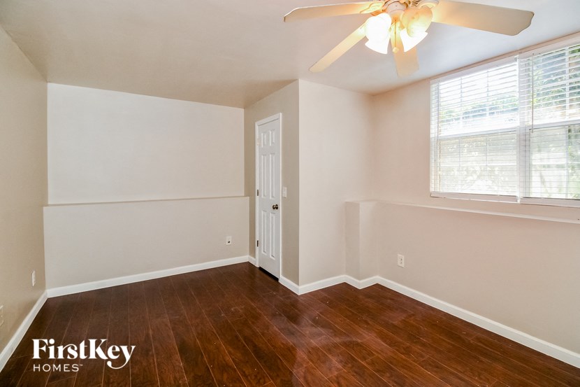 the living room of an empty home with wood flooring and a ceiling fan