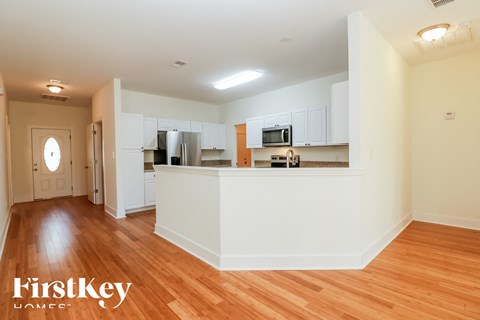 A kitchen with white cabinets and a wooden floor.