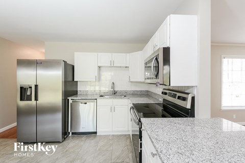 a white kitchen with stainless steel appliances and marble counter tops