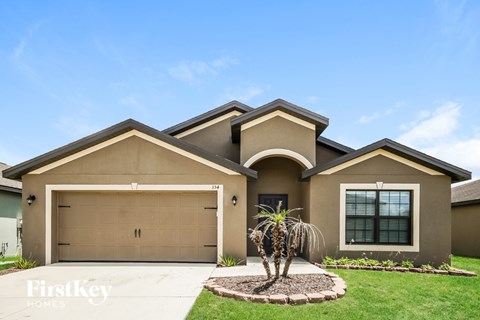A house with a brown garage door and a palm tree in front.