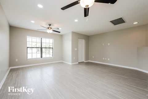A spacious room with a ceiling fan and lighting fixtures.