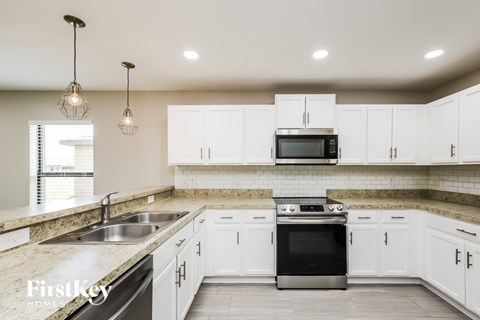 A modern kitchen with white cabinets and a stainless steel oven.