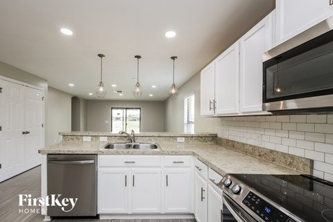 A kitchen with white cabinets and a black stove top oven.