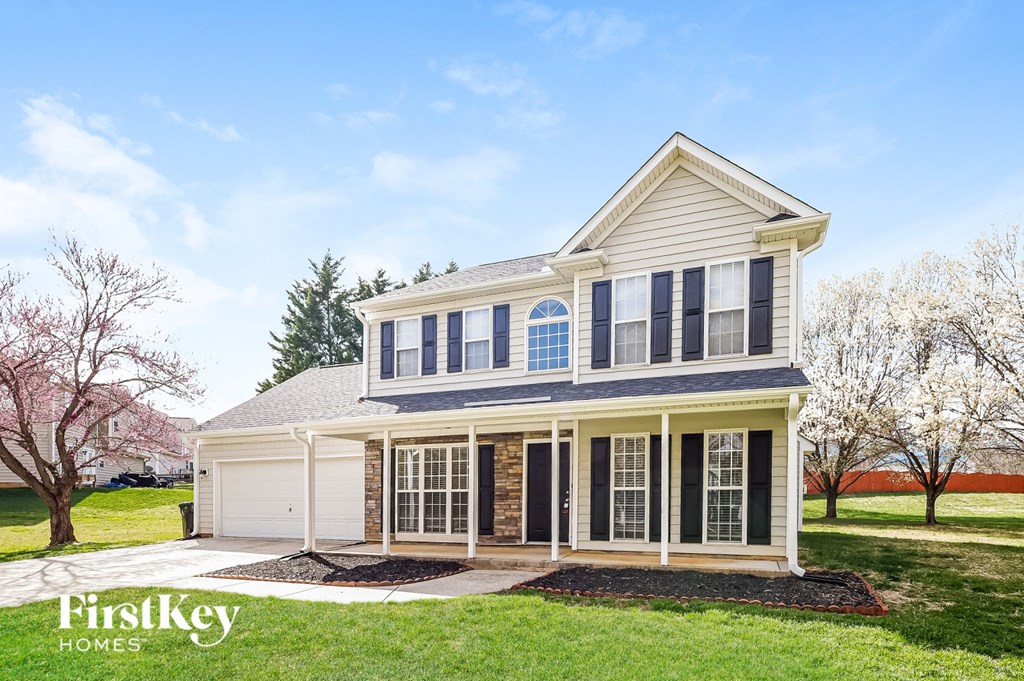A two-story house with a garage and a covered porch.