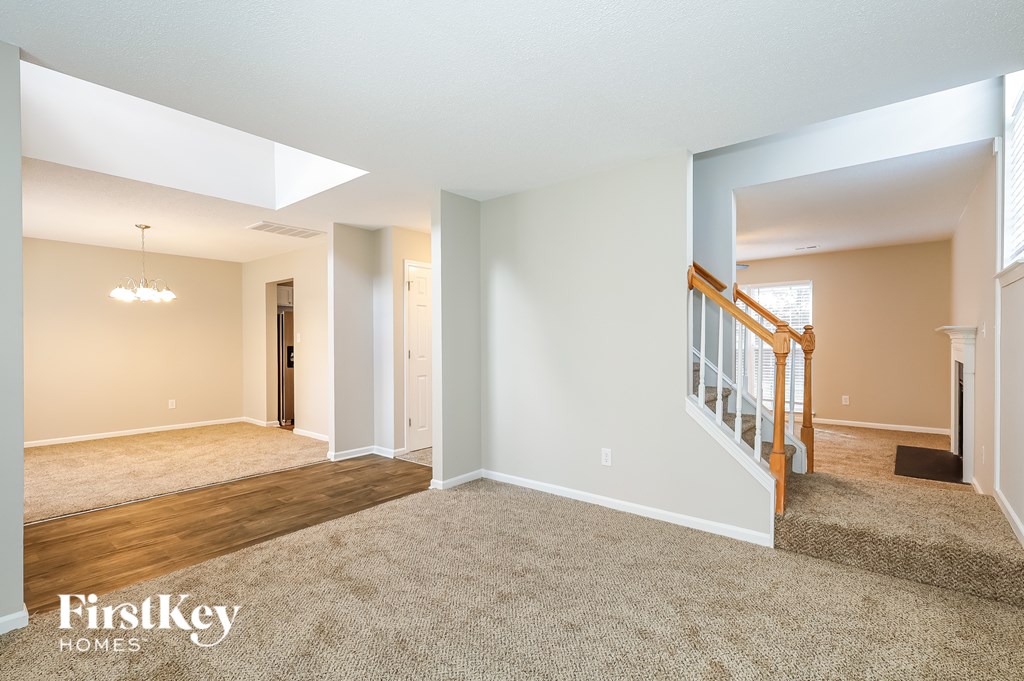 A spacious empty room with a staircase leading to the second floor.