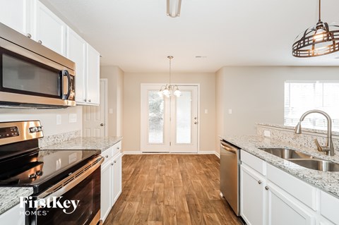 A kitchen with white cabinets and a wooden floor.