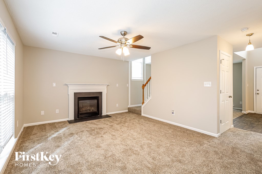 A spacious living room with a fireplace and a ceiling fan.