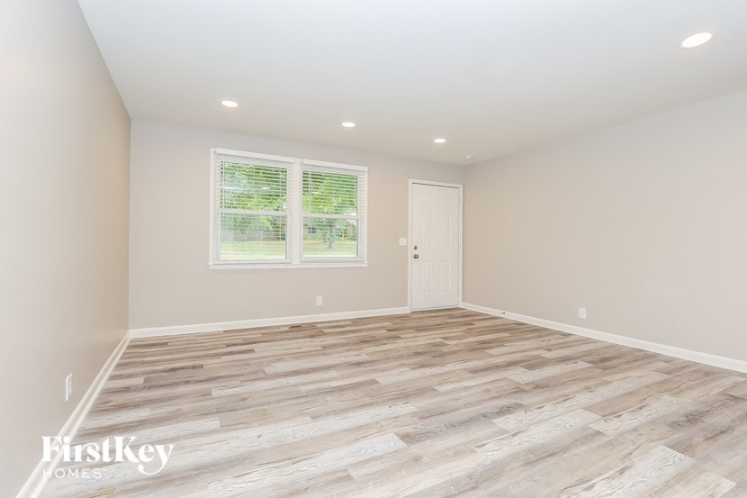 A room with wooden flooring and a window with blinds.